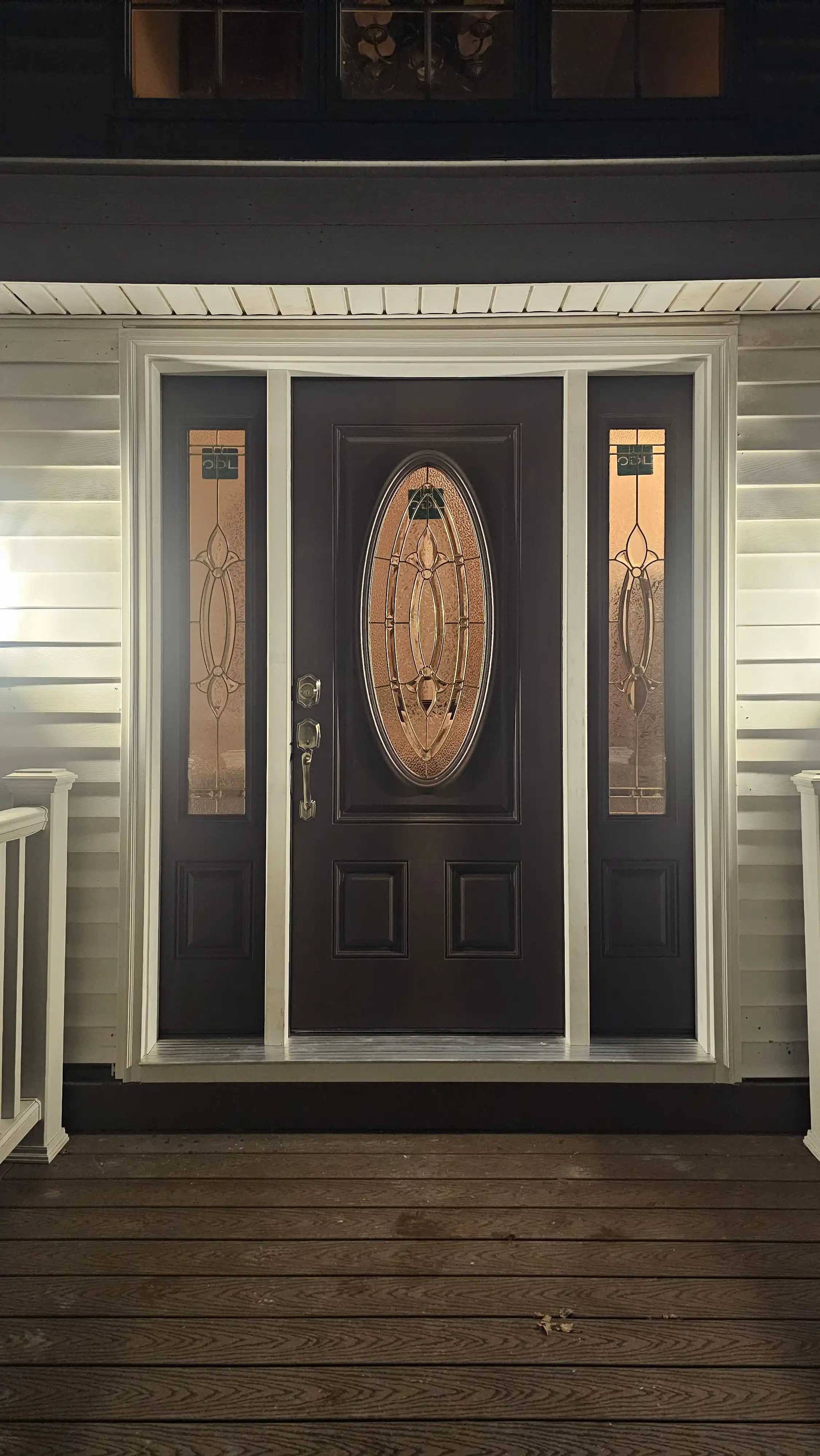 Dark wooden door with an oval glass insert and intricate sidelites