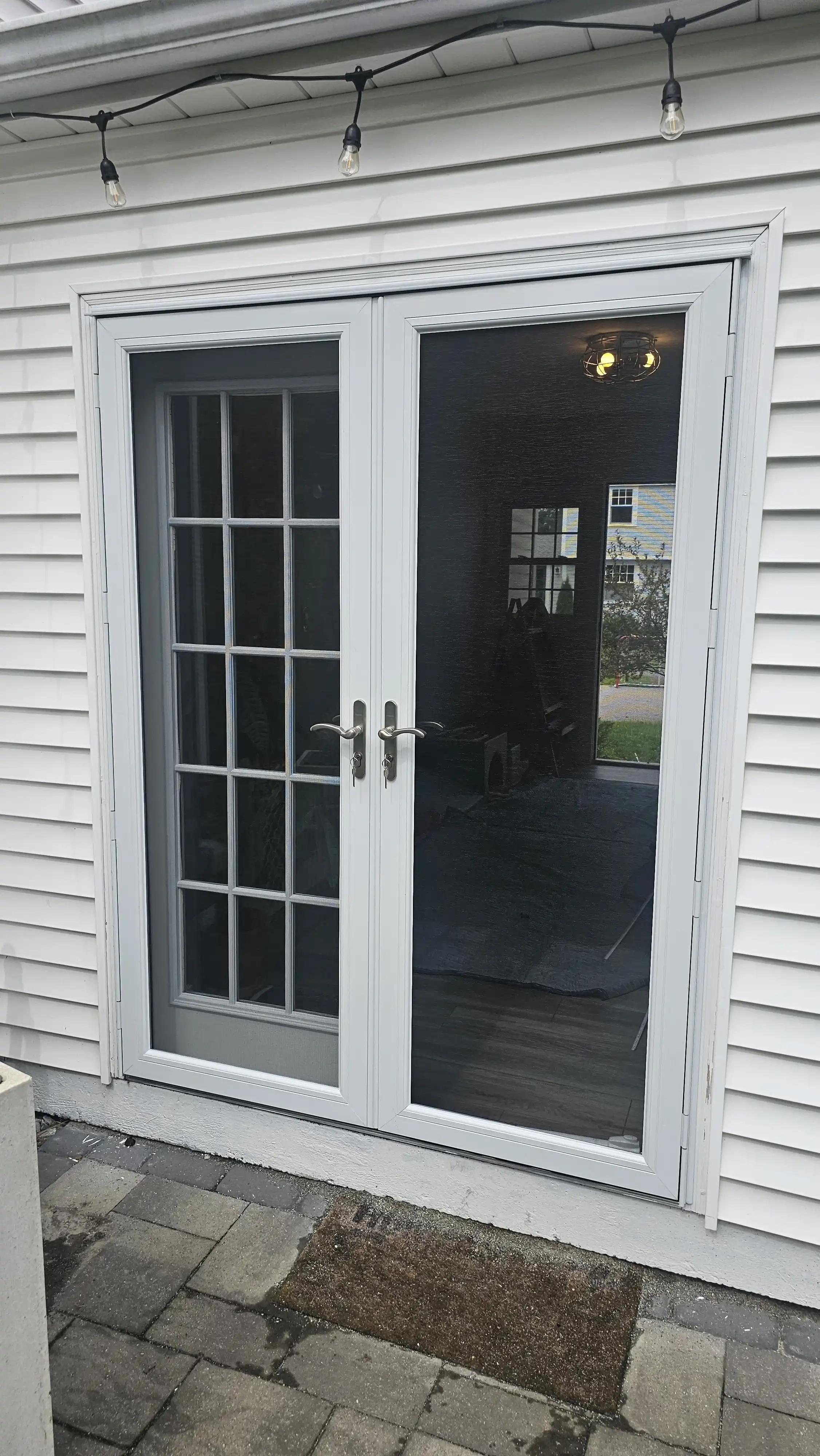 White double storm doors with glass panels, one side with grid design