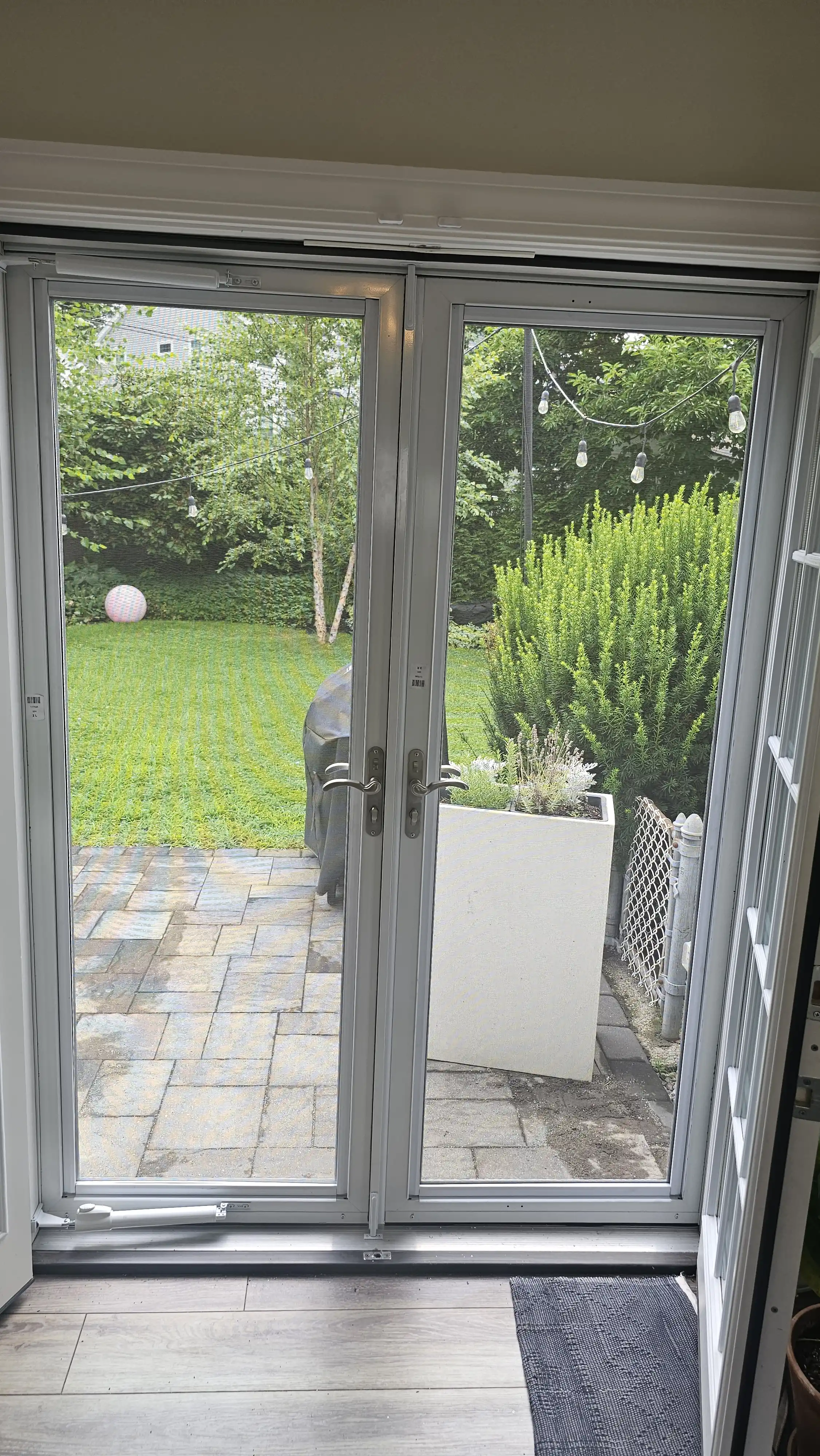 Interior view of white double storm doors with full glass panels and backyard view