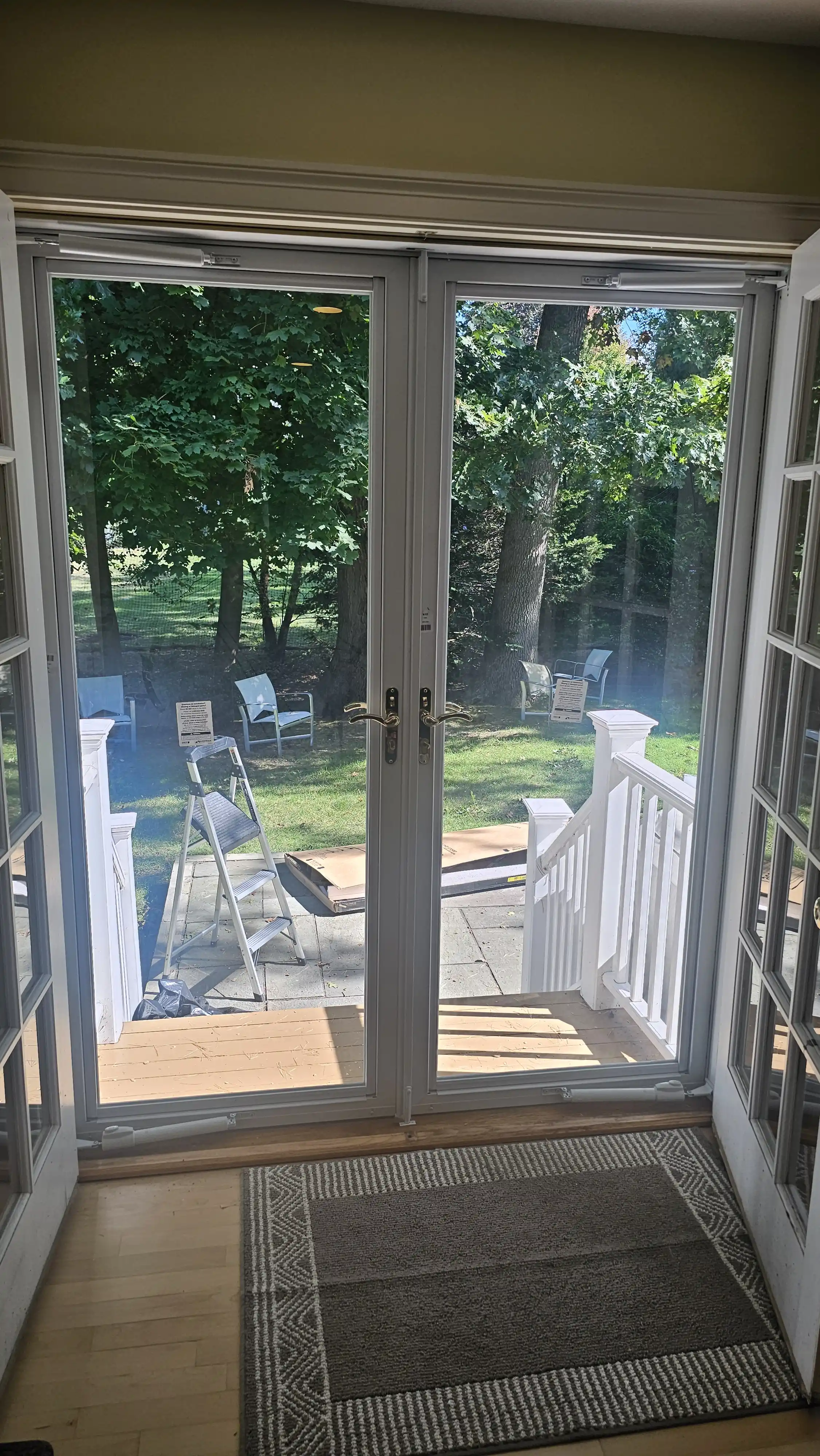 White patio storm doors with double handles and outdoor scenery
