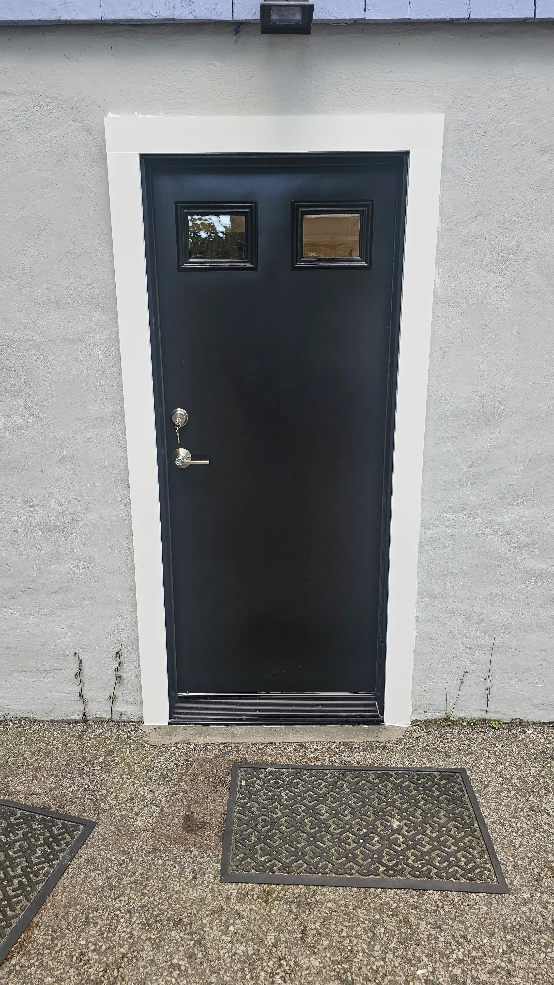 Black steel entry door with two small square windows near the top