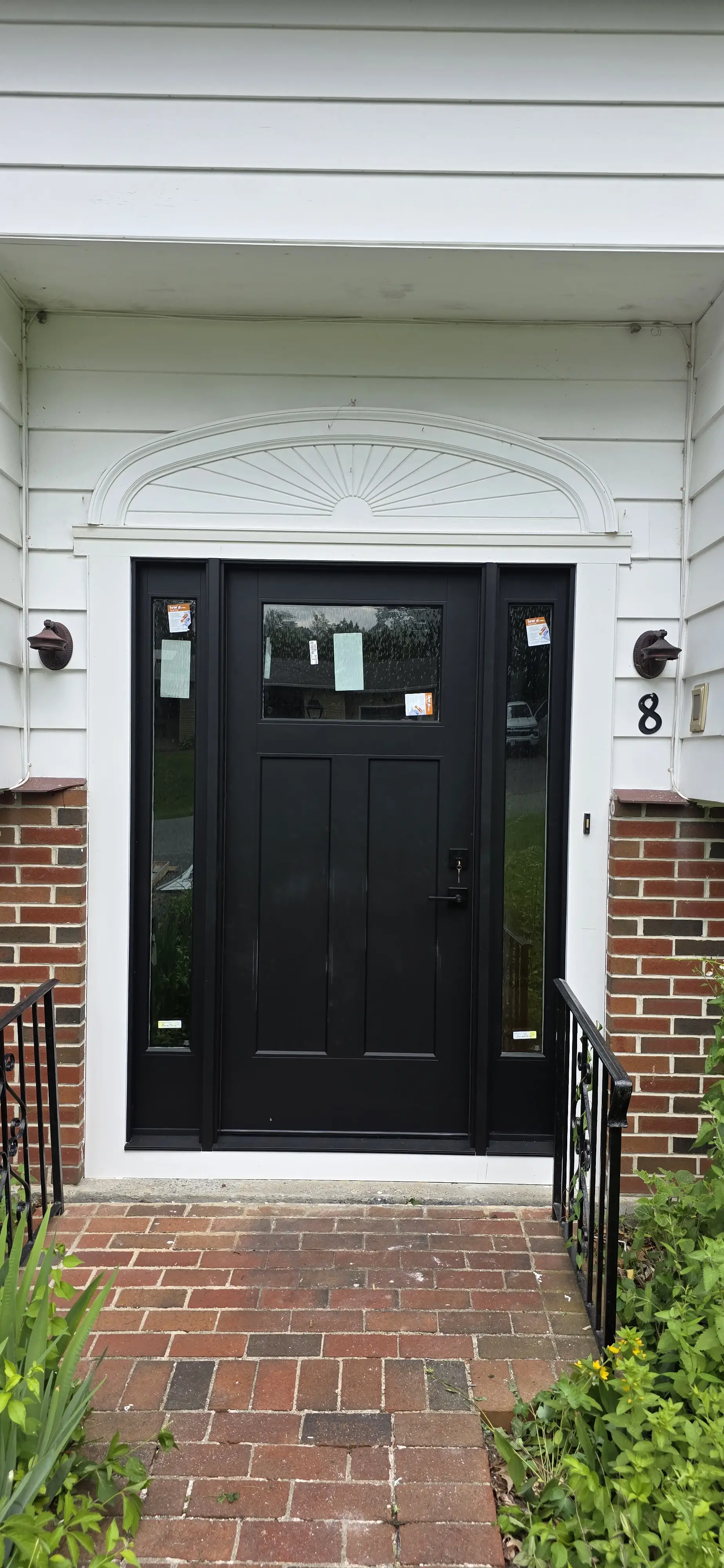 Black front entry door with two vertical sidelights and a top transom window