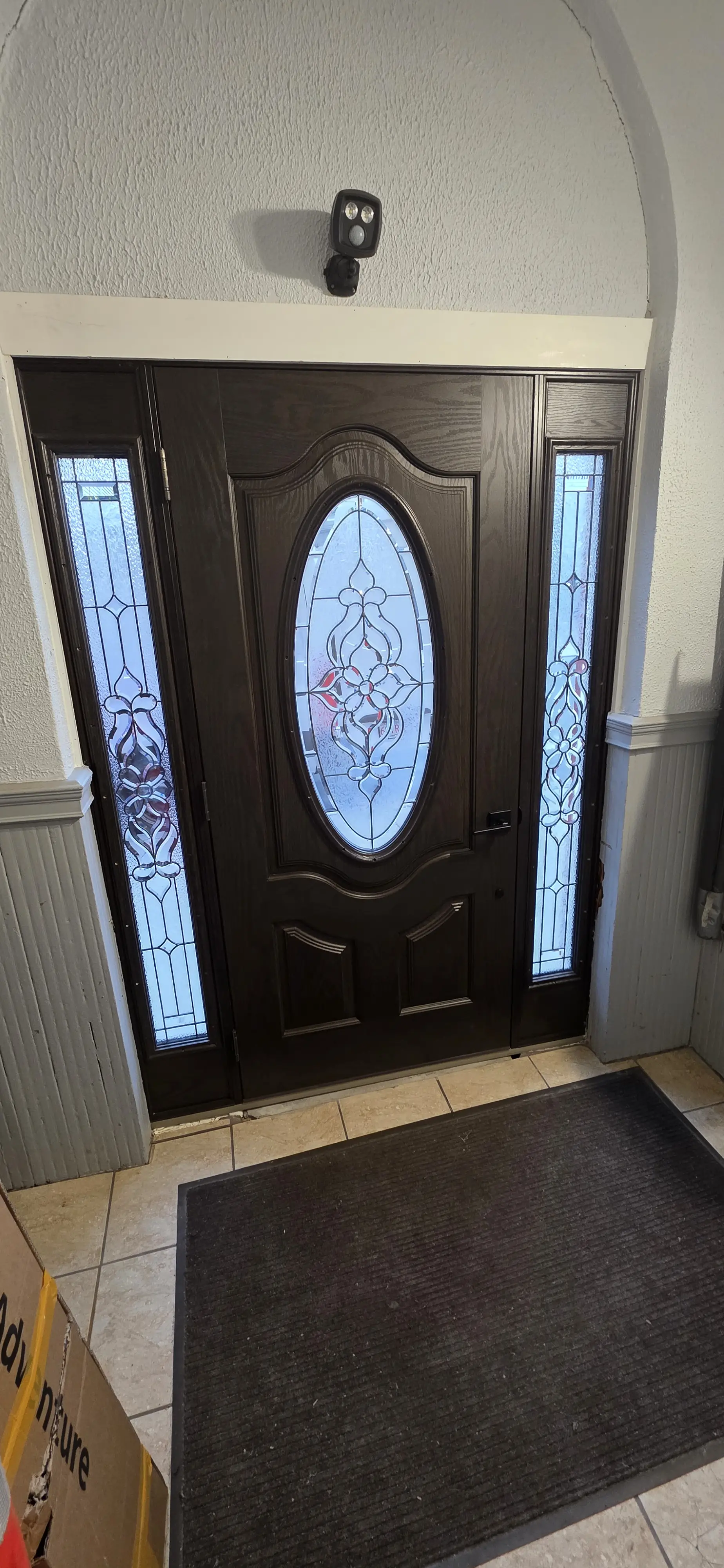 Decorative front entry door with oval glass and blue patterned sidelights