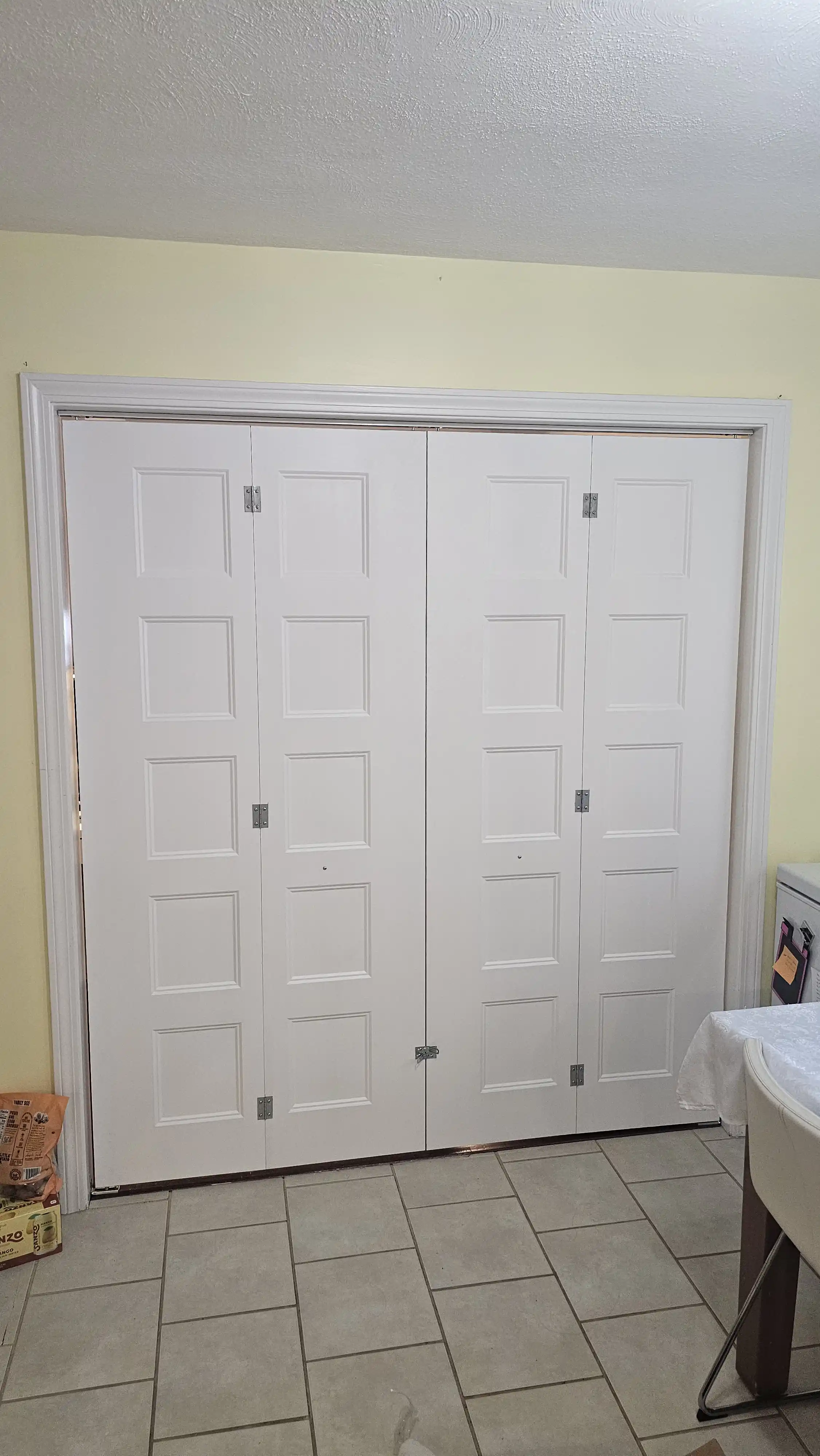 Four-panel white bi-fold closet doors with deep rectangular insets and subtle detailing