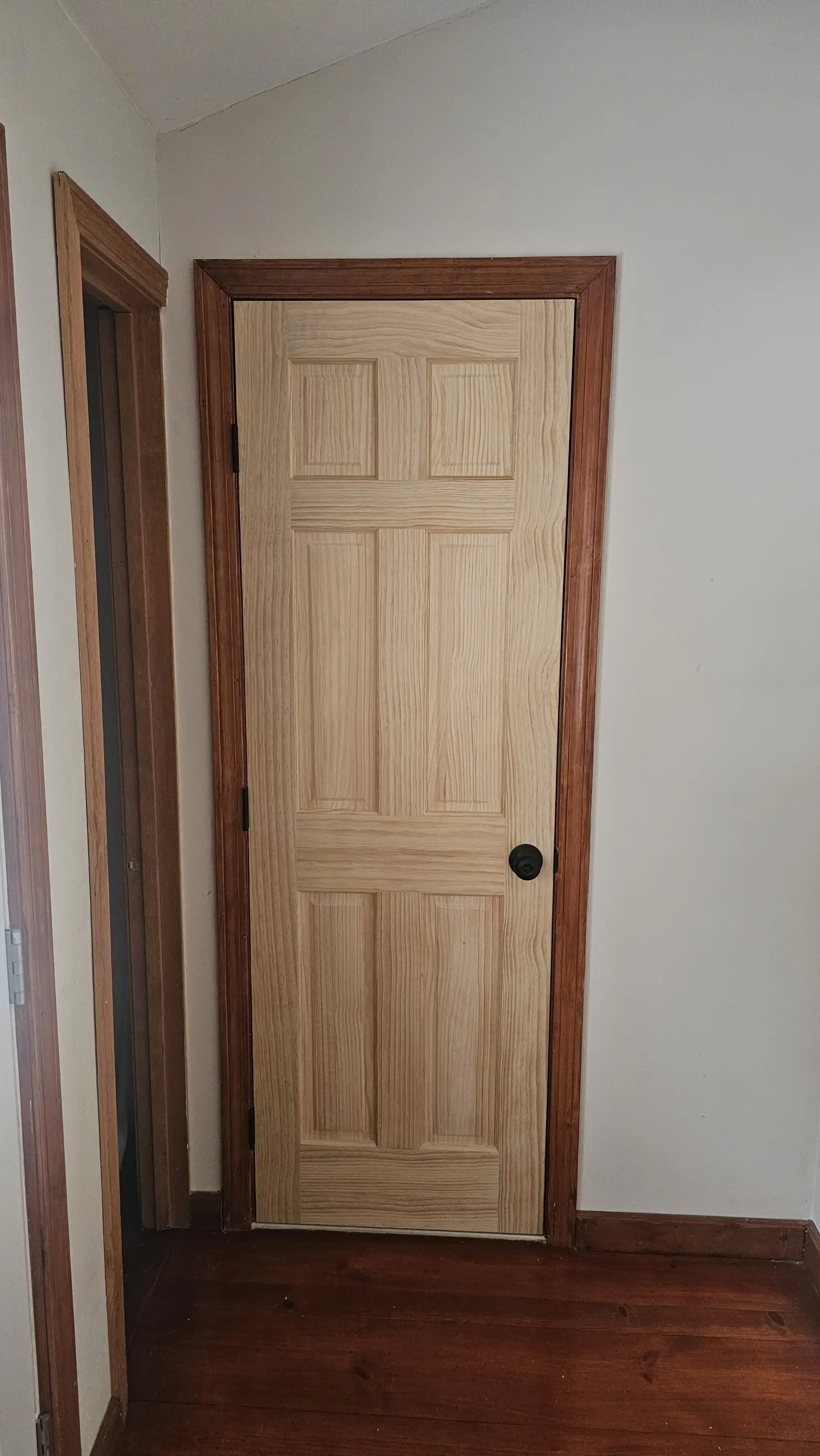 White interior door with two panels, the upper one arched, brass hinges