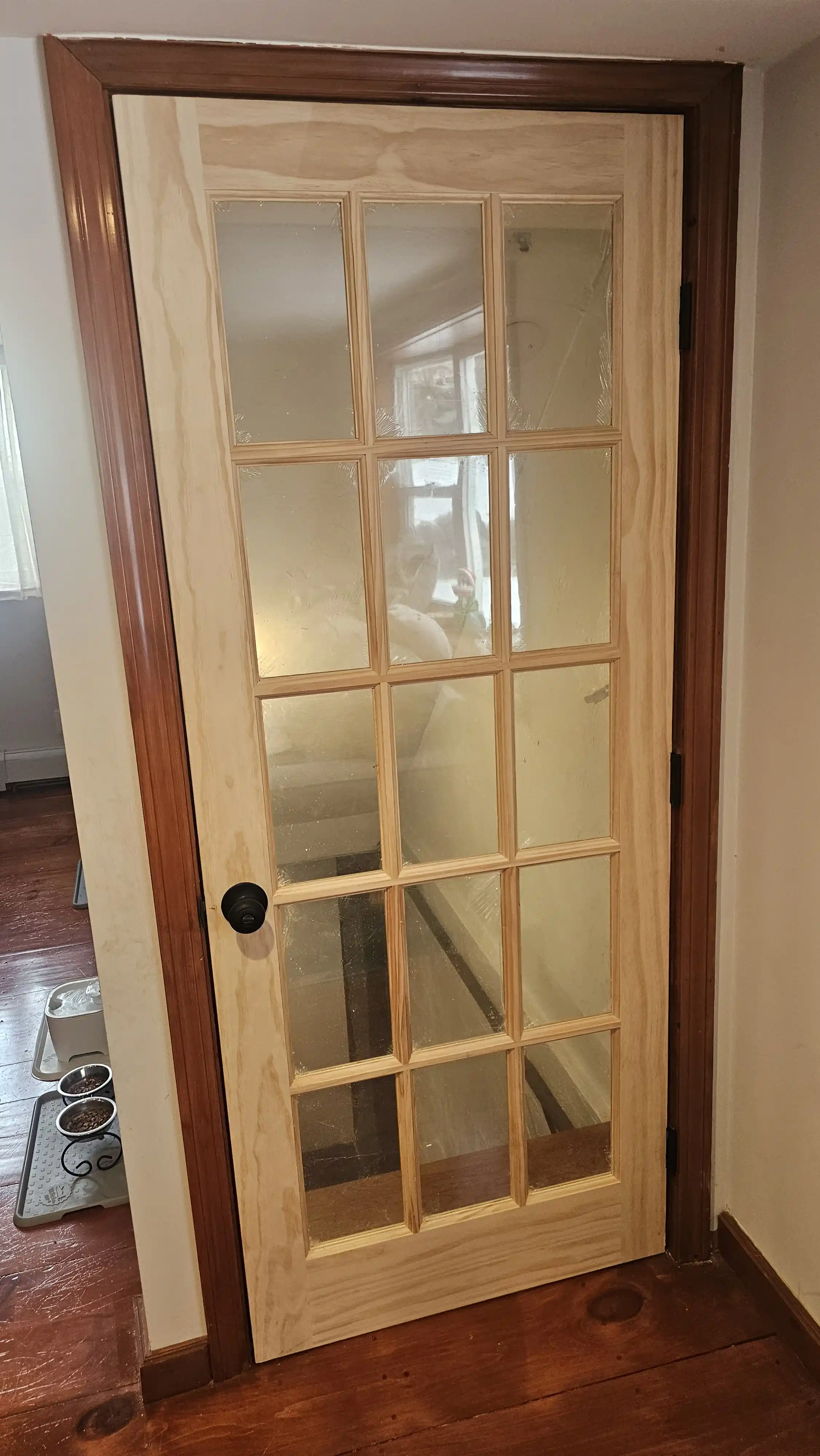 Six-panel white door with unfinished wooden trim, silver knob on right