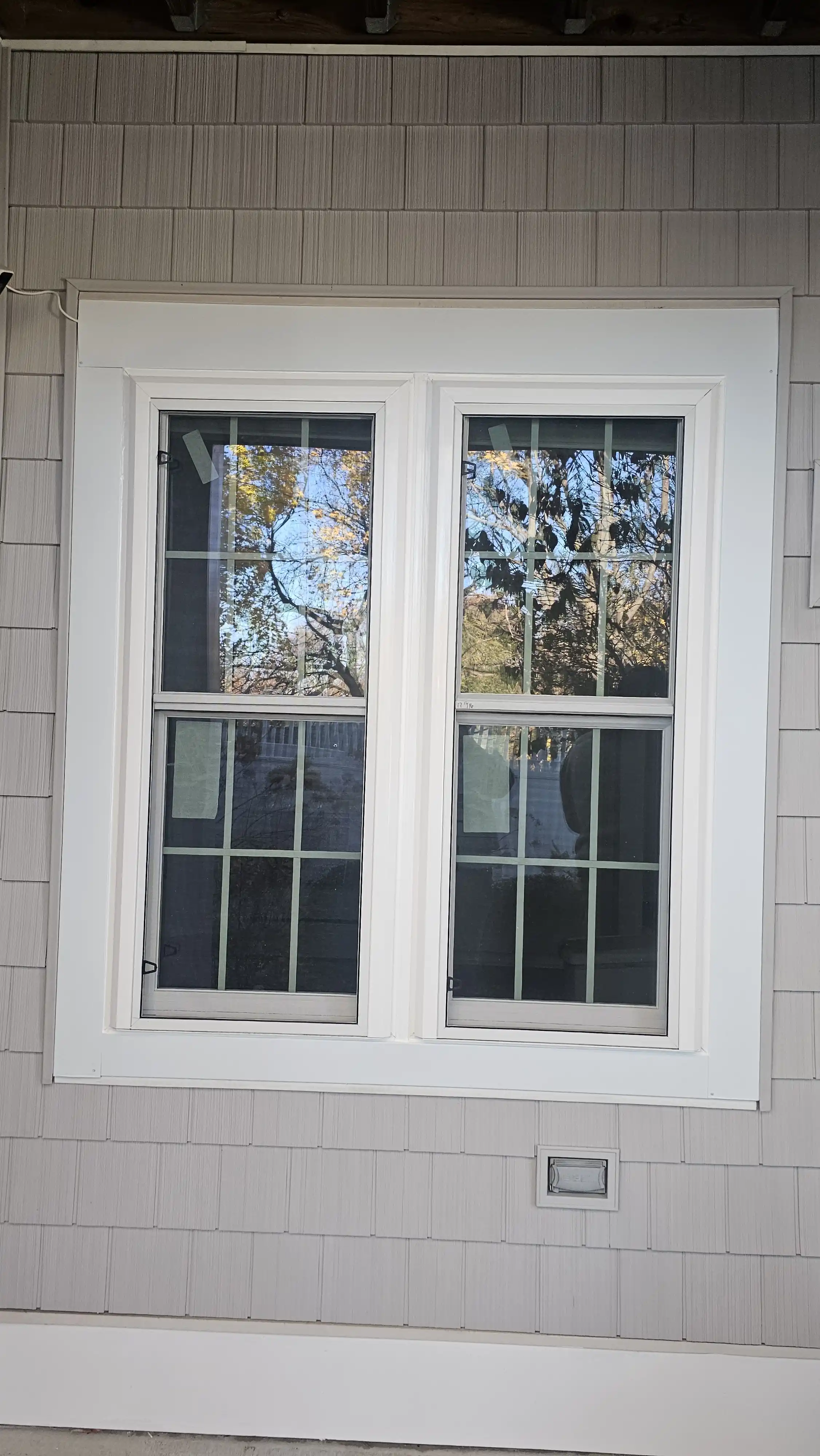 Double-hung window with white trim and grid pattern on glass