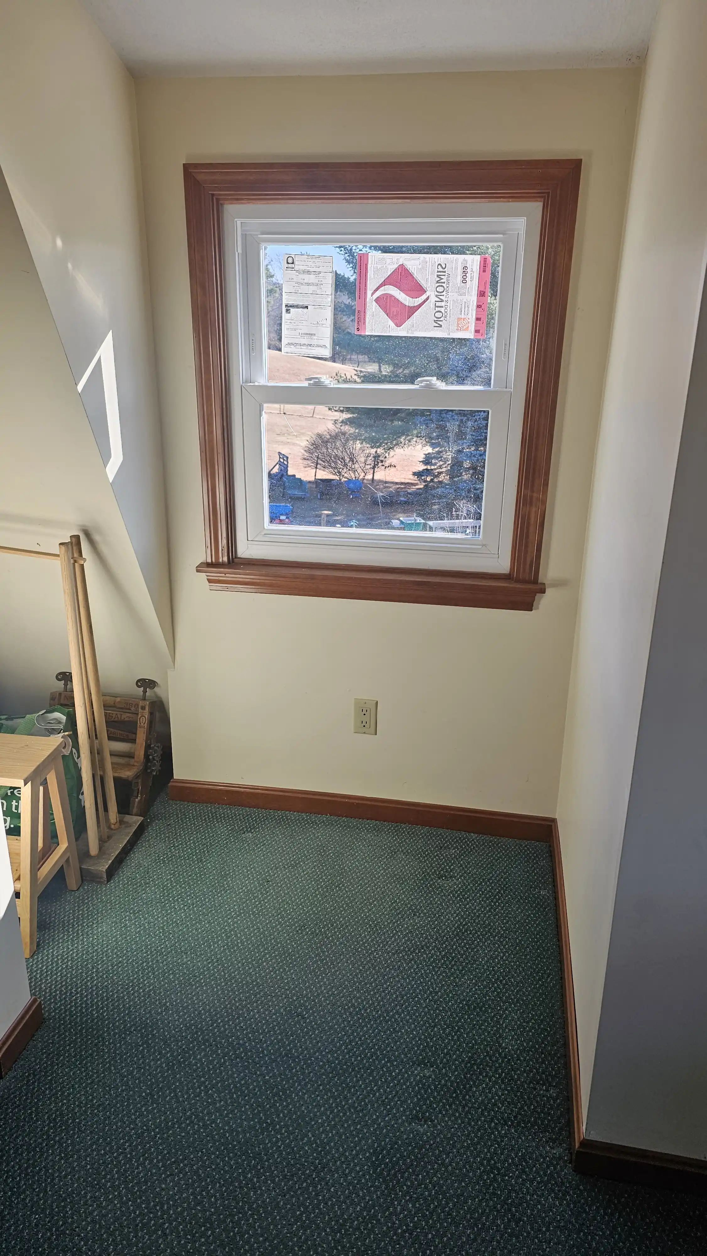 Single-hung window with wooden trim and manufacturer labels