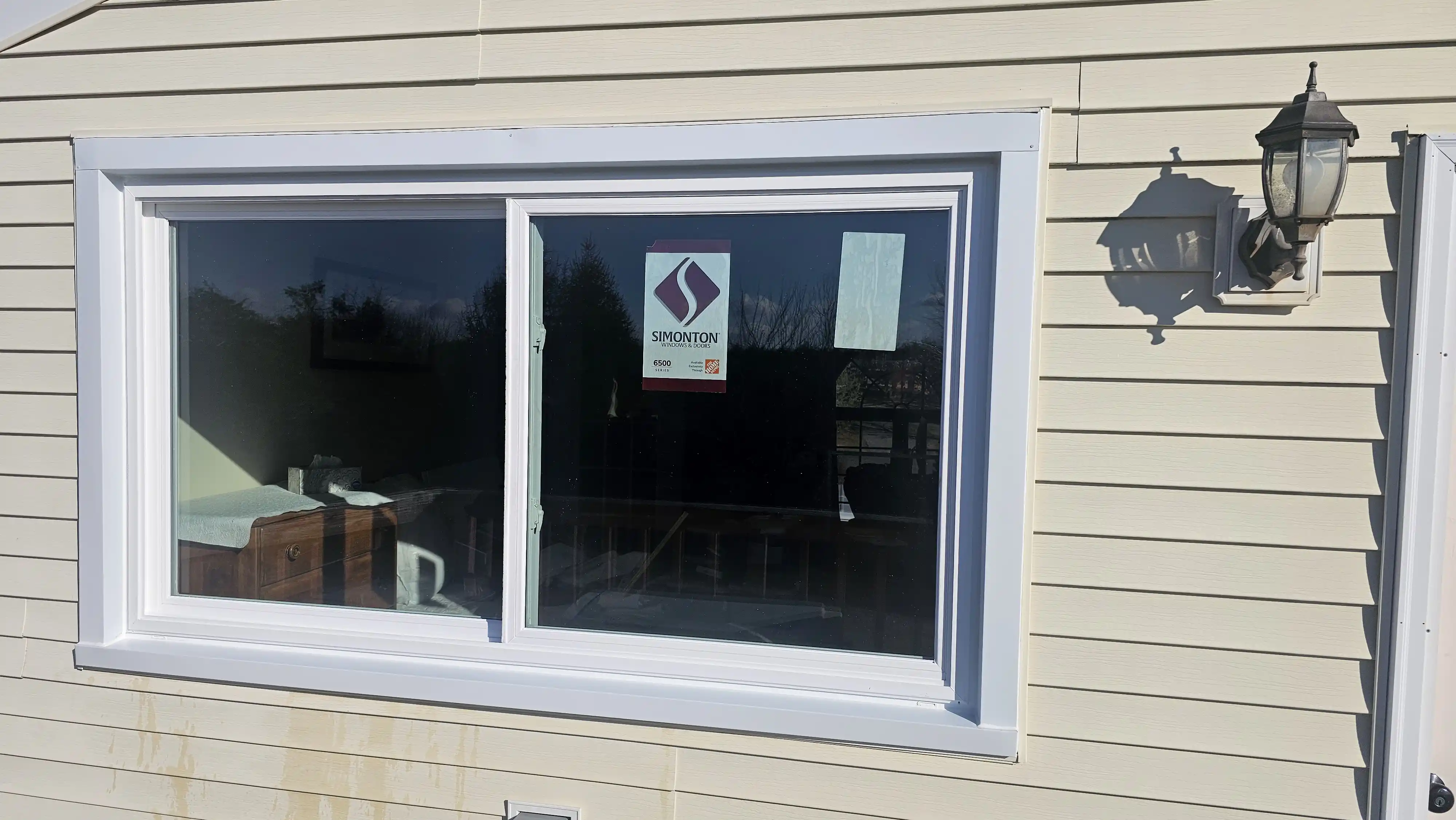 Sliding window with white frame and manufacturer sticker on glass