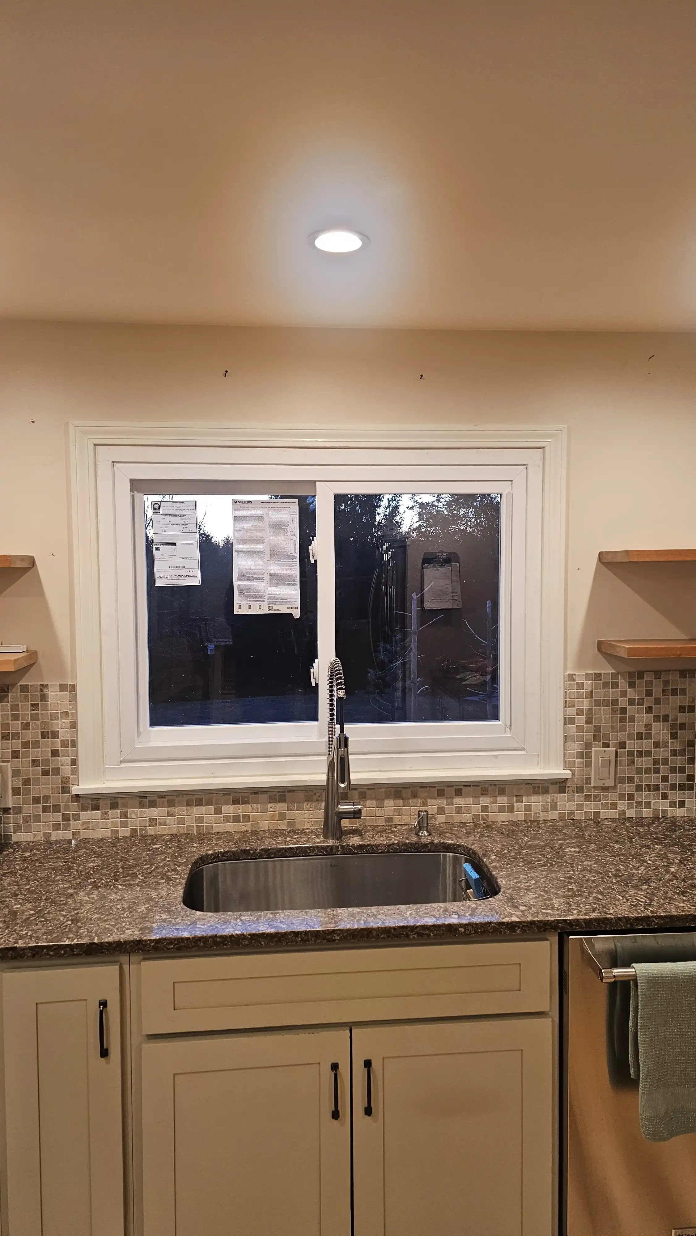 Kitchen sliding window with white trim installed above a sink