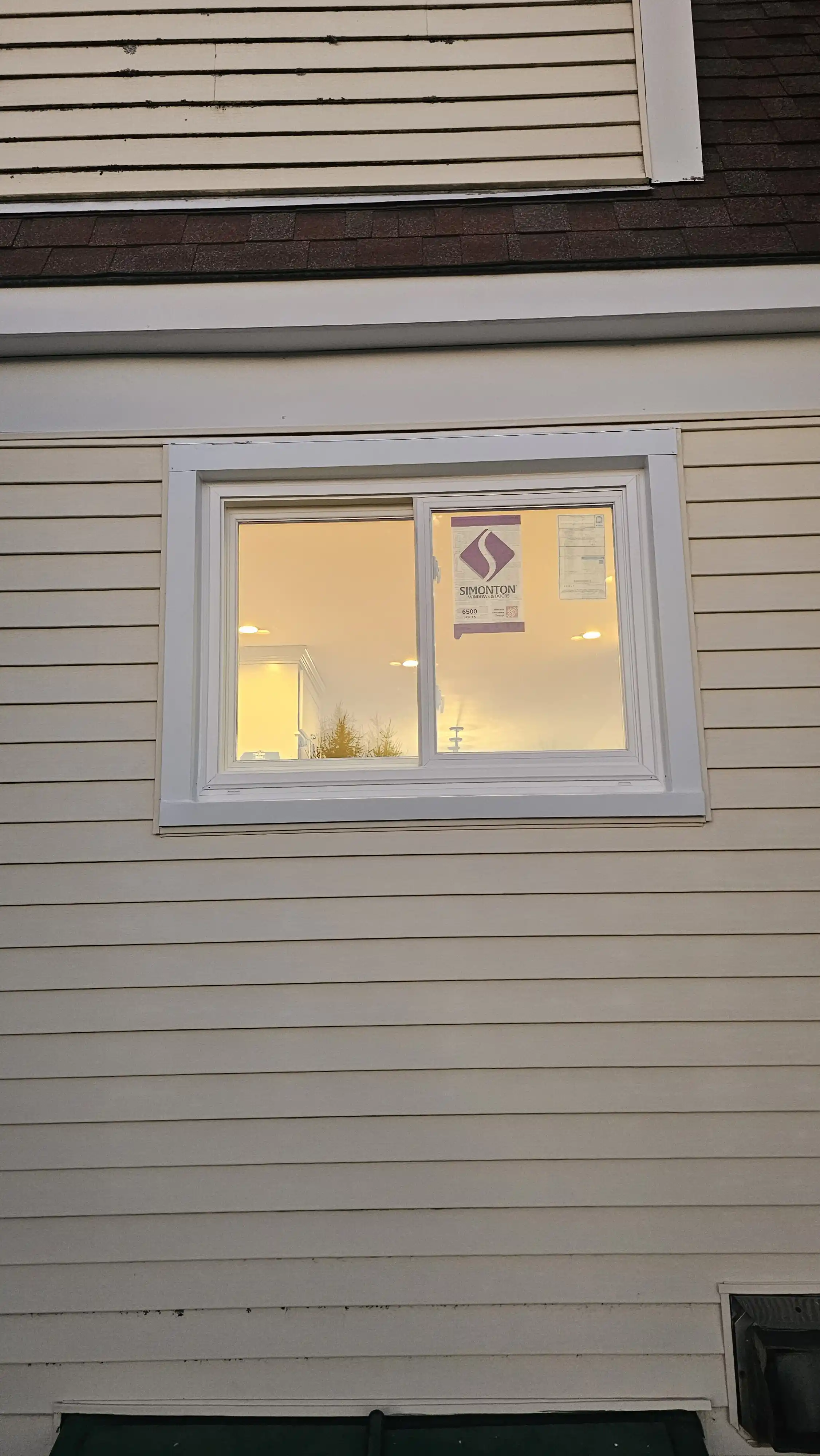 Small sliding window with white frame and brand label visible on glass
